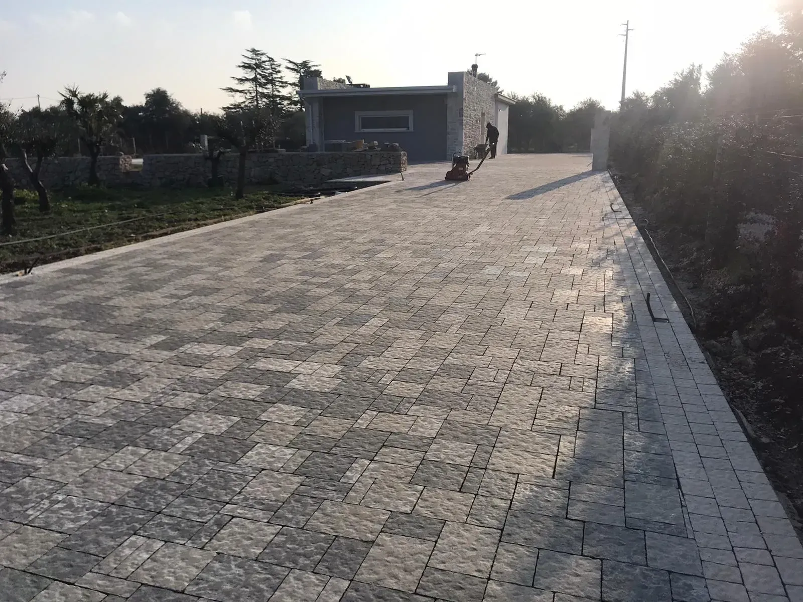 Vialetto di ghiaia che conduce a un edificio in pietra in una giornata di sole.