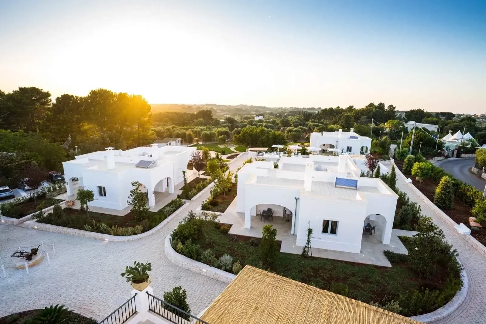 Ville bianche con porte ad arco e tetti piani in un paesaggio soleggiato e verde.