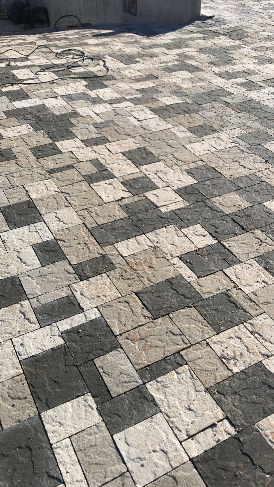 Patio pavimentato con motivo a scacchiera di pietre grigie e nere.