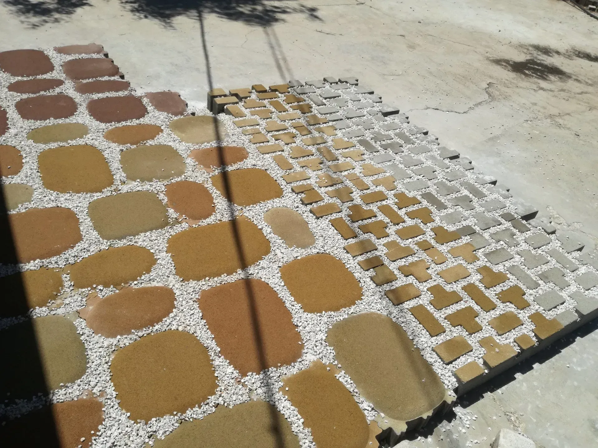 Tre disegni di pietre per pavimentazione su una superficie di cemento: pietre marroni, beige e beige separate da ciottoli bianchi.