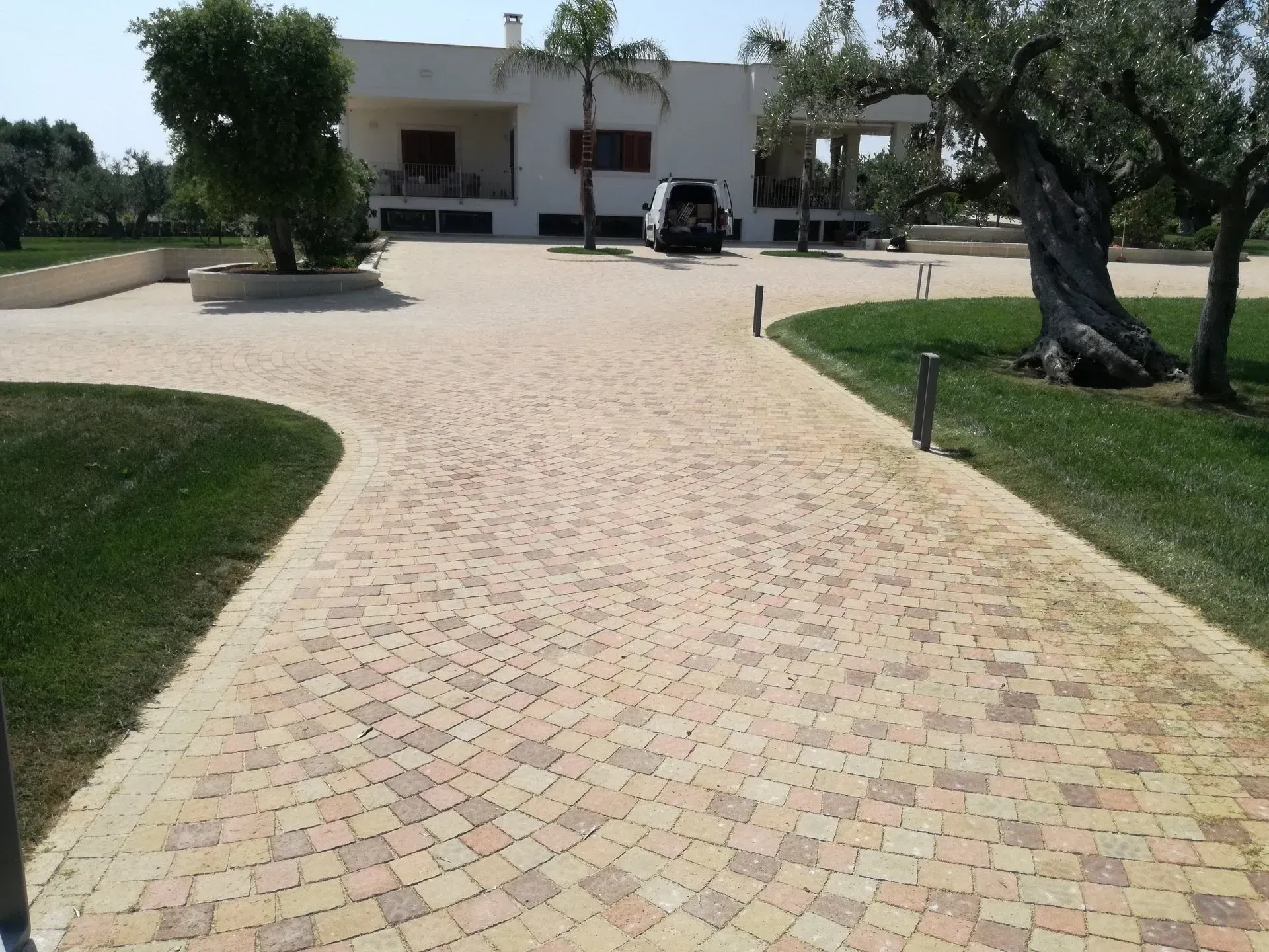 Vialetto di mattoni che conduce a una casa bianca con un'auto parcheggiata di fronte.