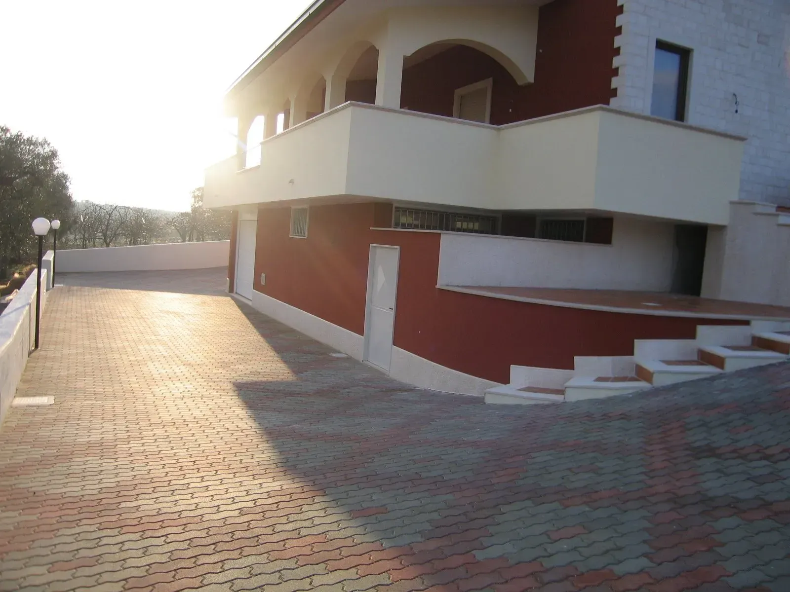 Un edificio a due piani con facciata rossa e beige. Un vialetto in mattoni in primo piano.