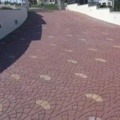 Vialetto in mattoni con motivo circolare e accenti color marrone chiaro, accanto a un muro bianco.