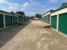 A row of green garage doors are lined up in a parking lot.