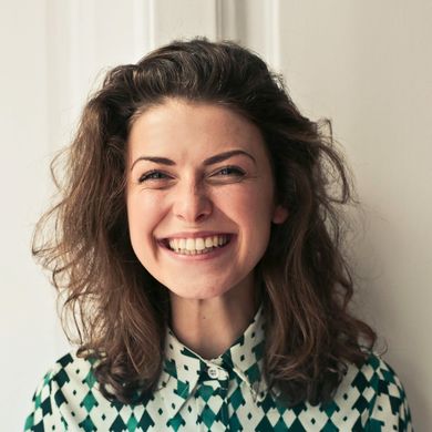 A woman wearing a green and white checkered shirt is smiling