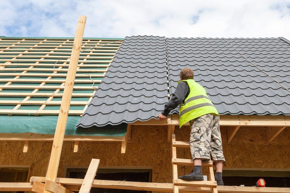 Worker Installing Gray Roof Shingles On A House Under Construction — iFix Roofing Geelong In South Geelong, VIC