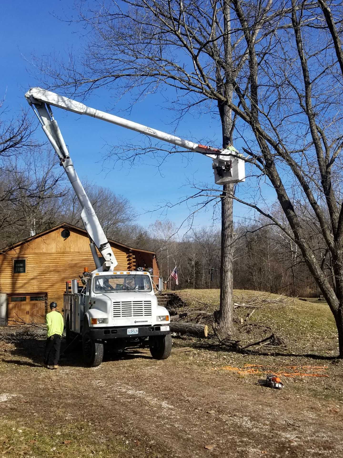 A man is standing next to a truck with a crane attached to it.