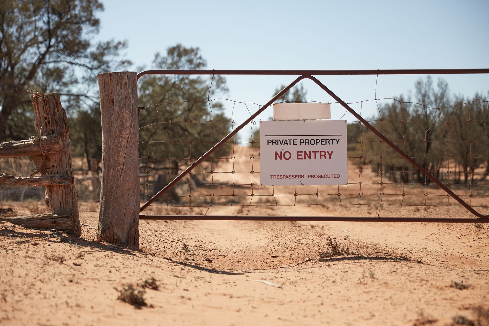 A no entry sign is posted on a gate in the desert