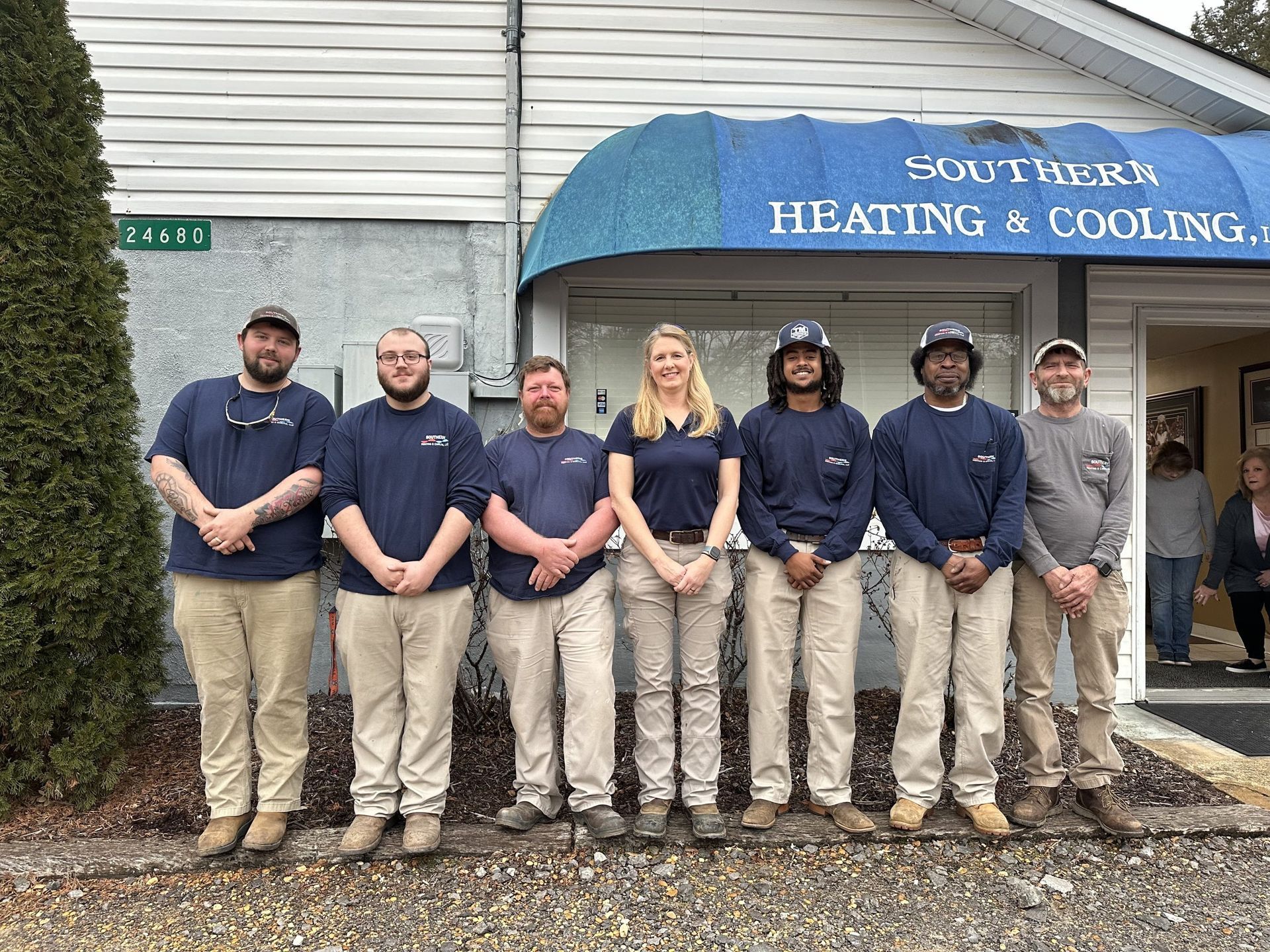 Group of seven employees in work uniforms, standing in front of Southern Heating & Cooling building.