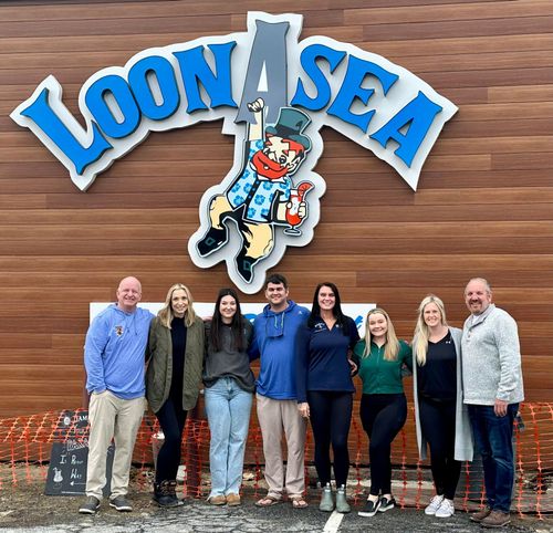 LoonAsea ownership and management sitting in front of new sign.