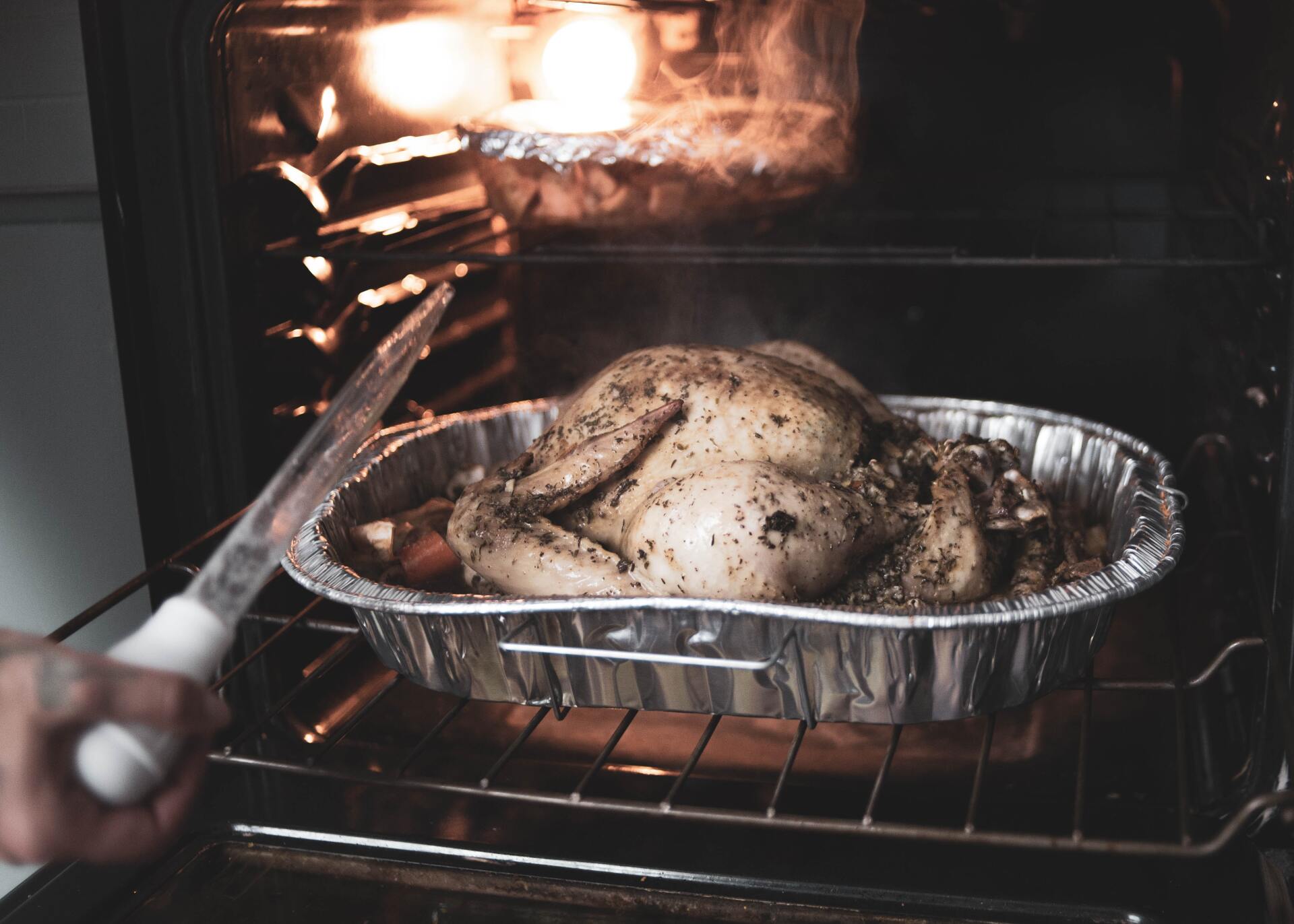 An open oven with a tray of raw chicken placed inside, ready for cooking.