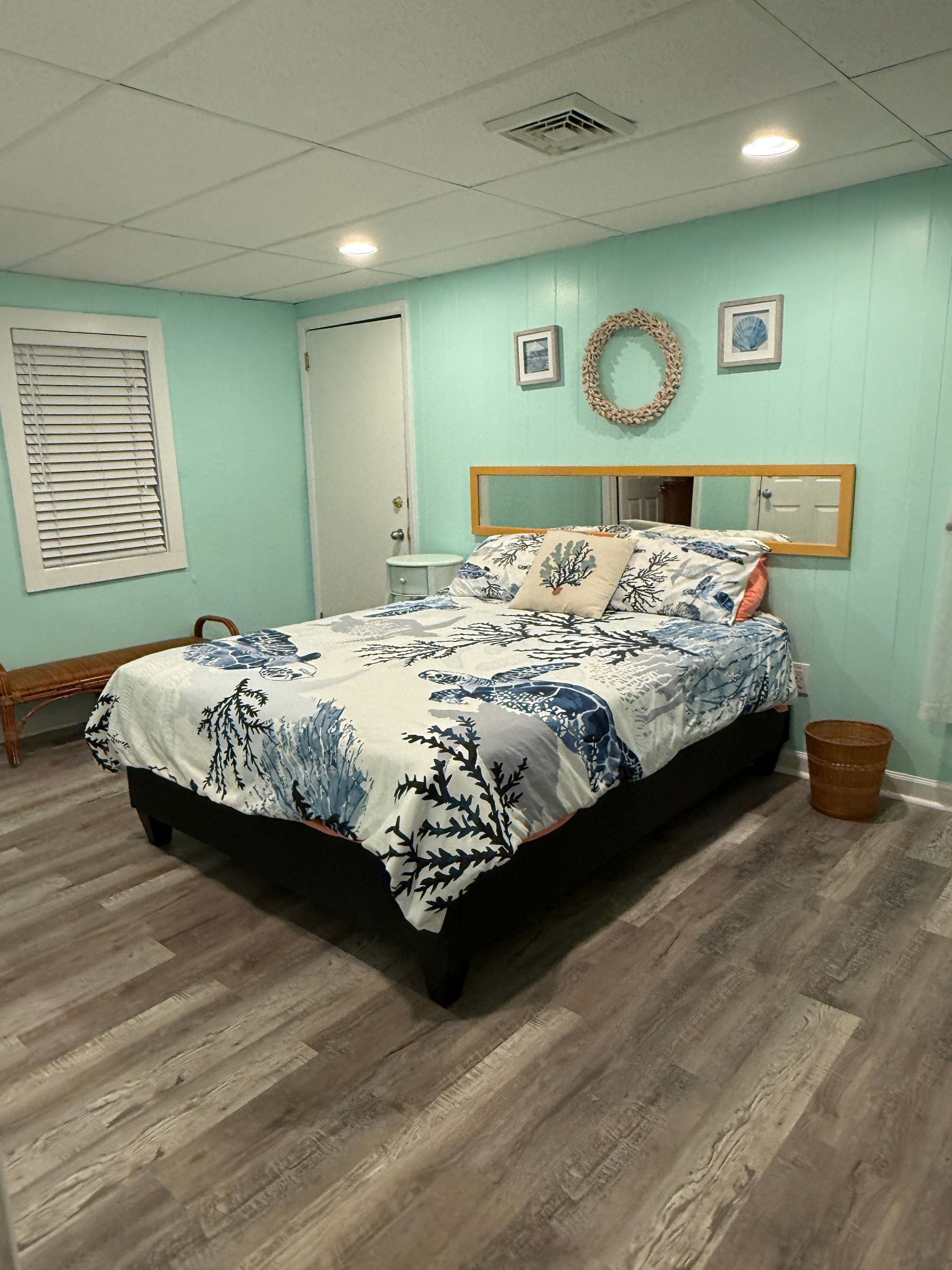 Bedroom with turquoise walls, bed with blue bedding, and a wreath above the headboard.