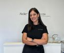 A woman in a black shirt is standing in front of a counter with her arms crossed.