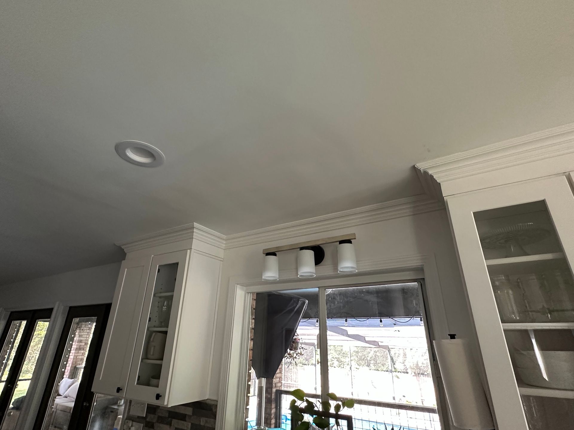 A kitchen with white cabinets , a window , and a ceiling light.