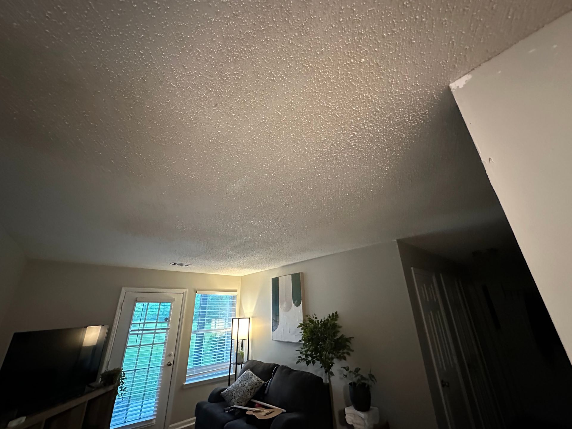 A living room with a couch , television , and sliding glass doors.