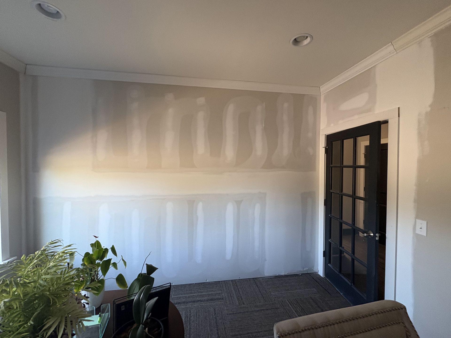 A living room with a couch , chair , plant and a door.