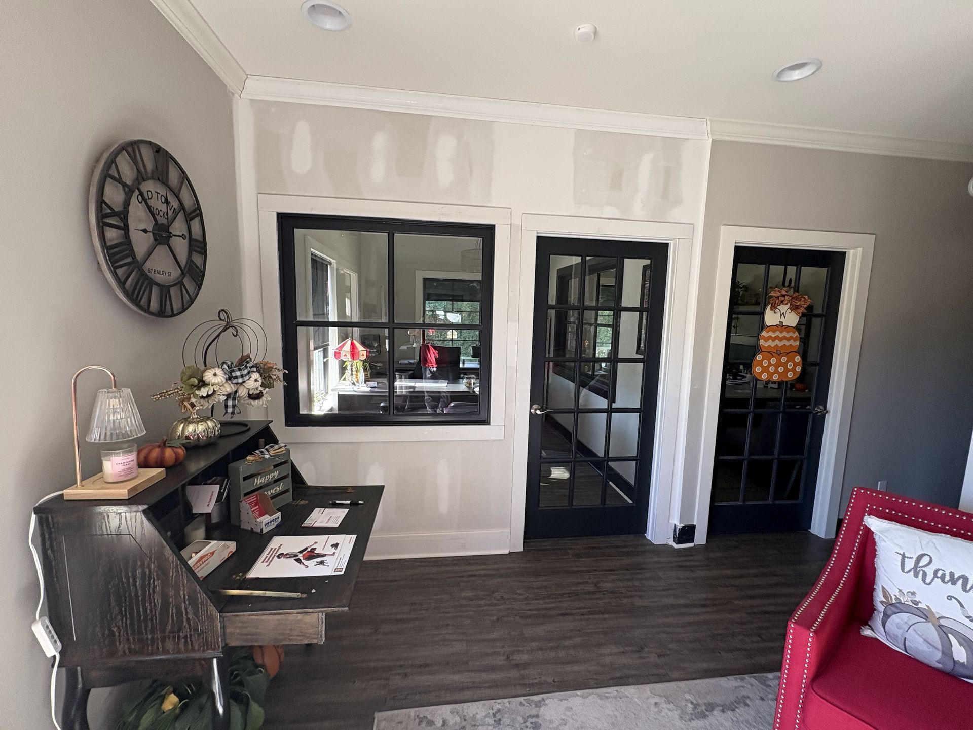 A living room with a desk and a clock on the wall.