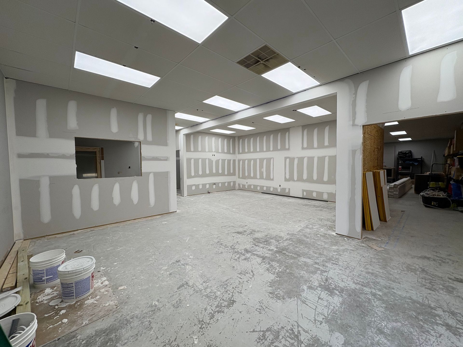 A large empty room with drywall walls and ceiling lights.
