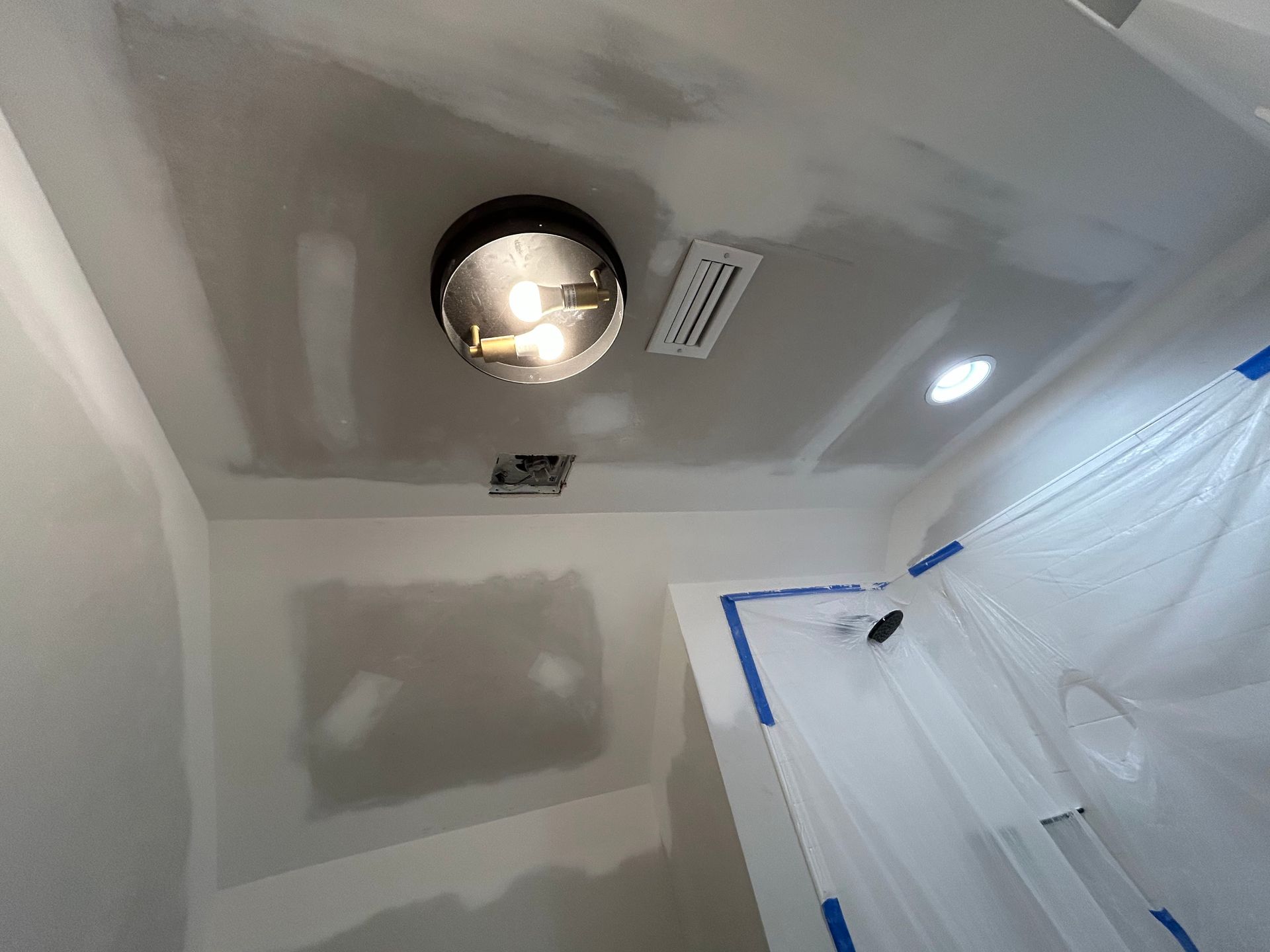 A bathroom with a light on the ceiling and a ladder.