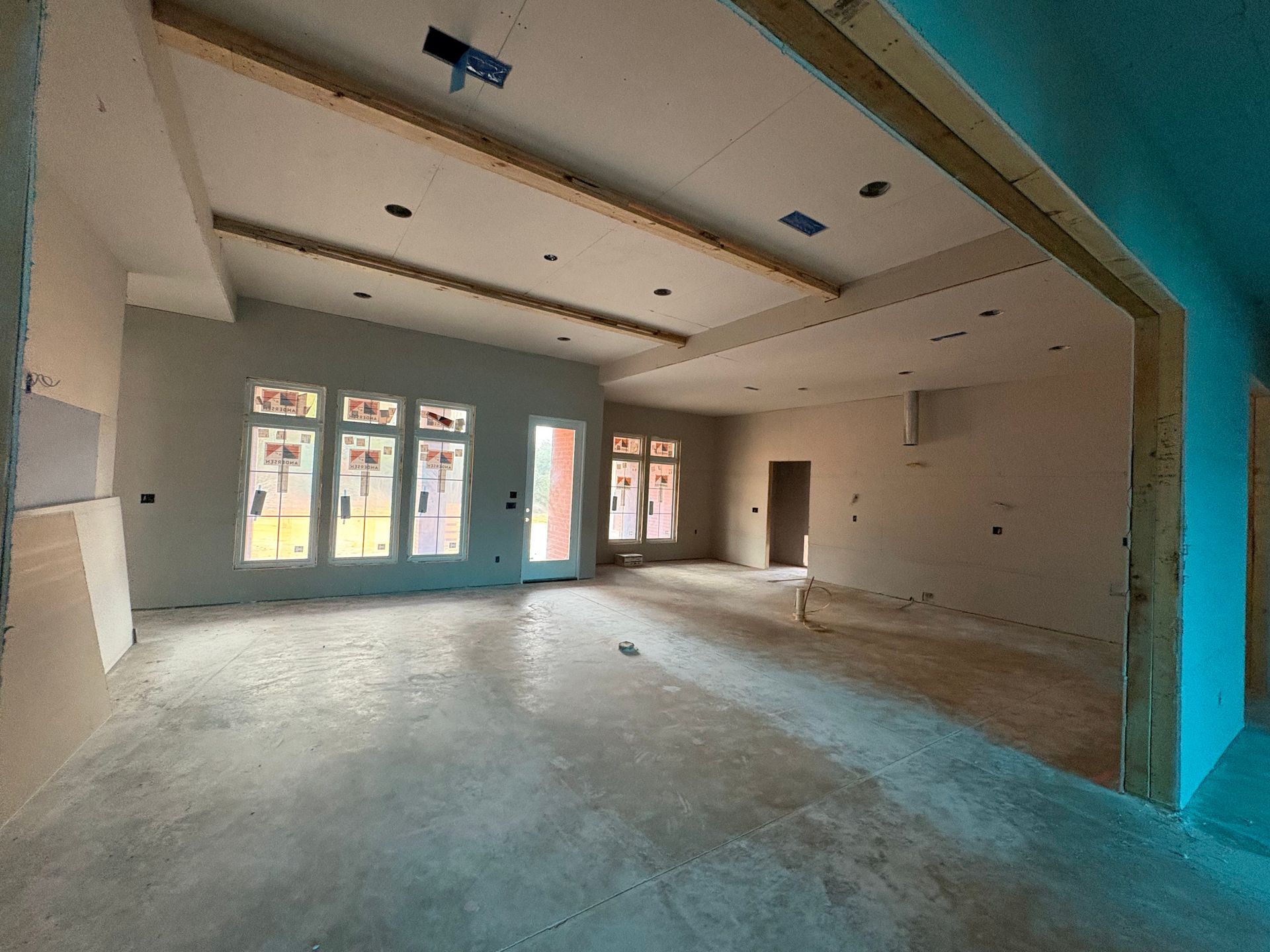 A large empty room with a lot of windows in a house under construction.