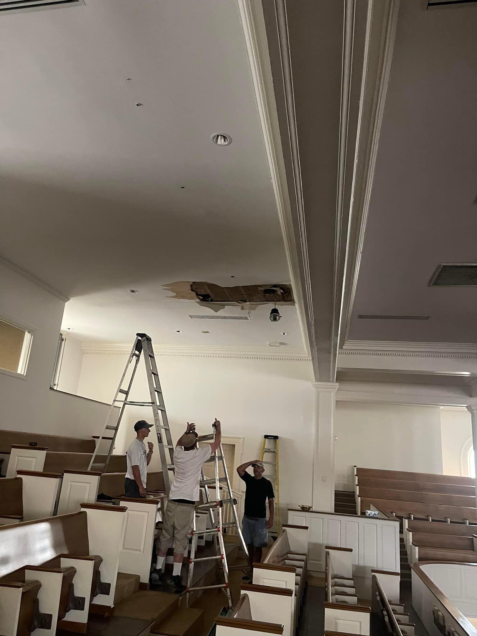 A group of men are working on the ceiling of a church.