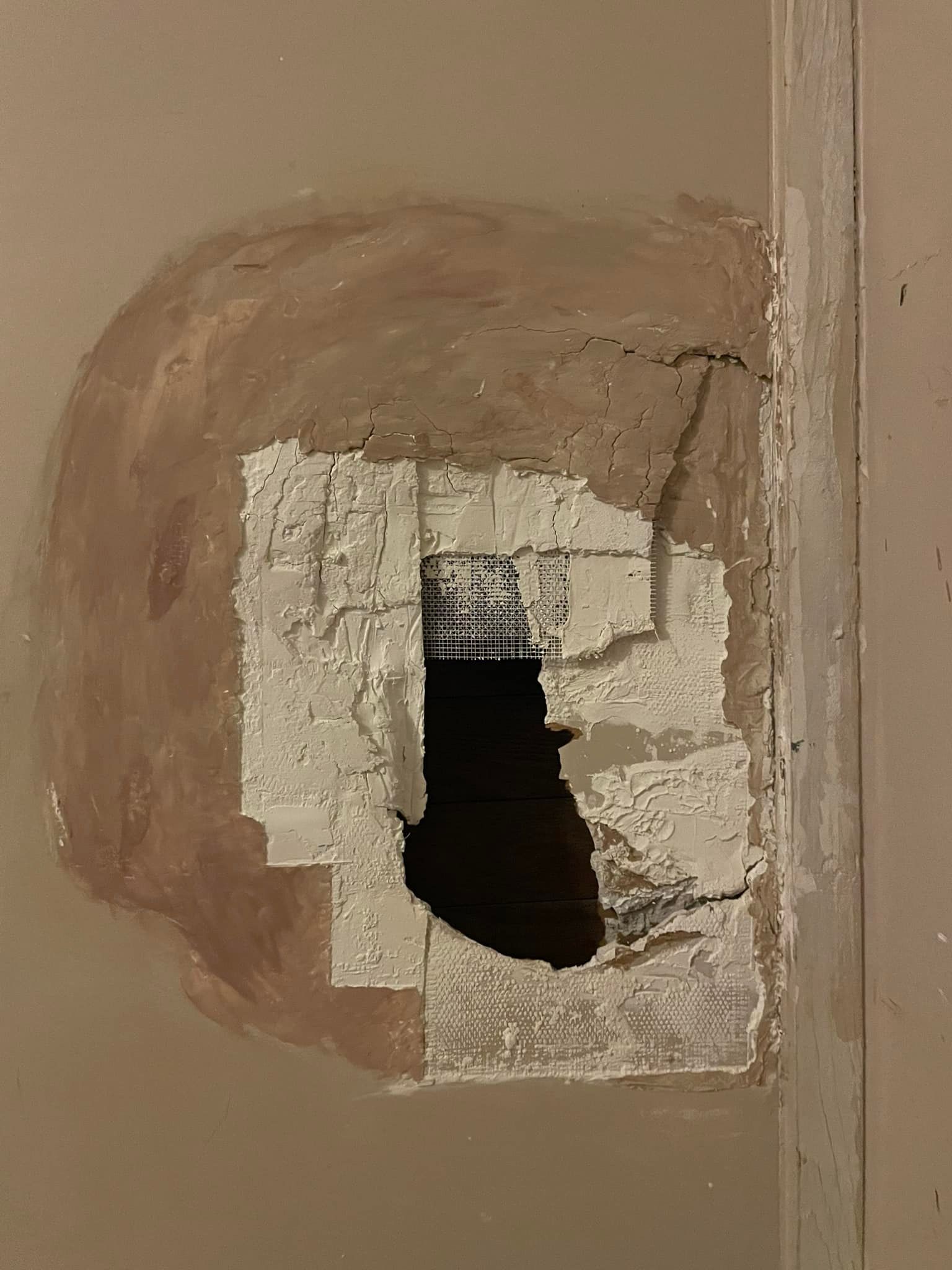 A hole in a wall with a bottle in it.