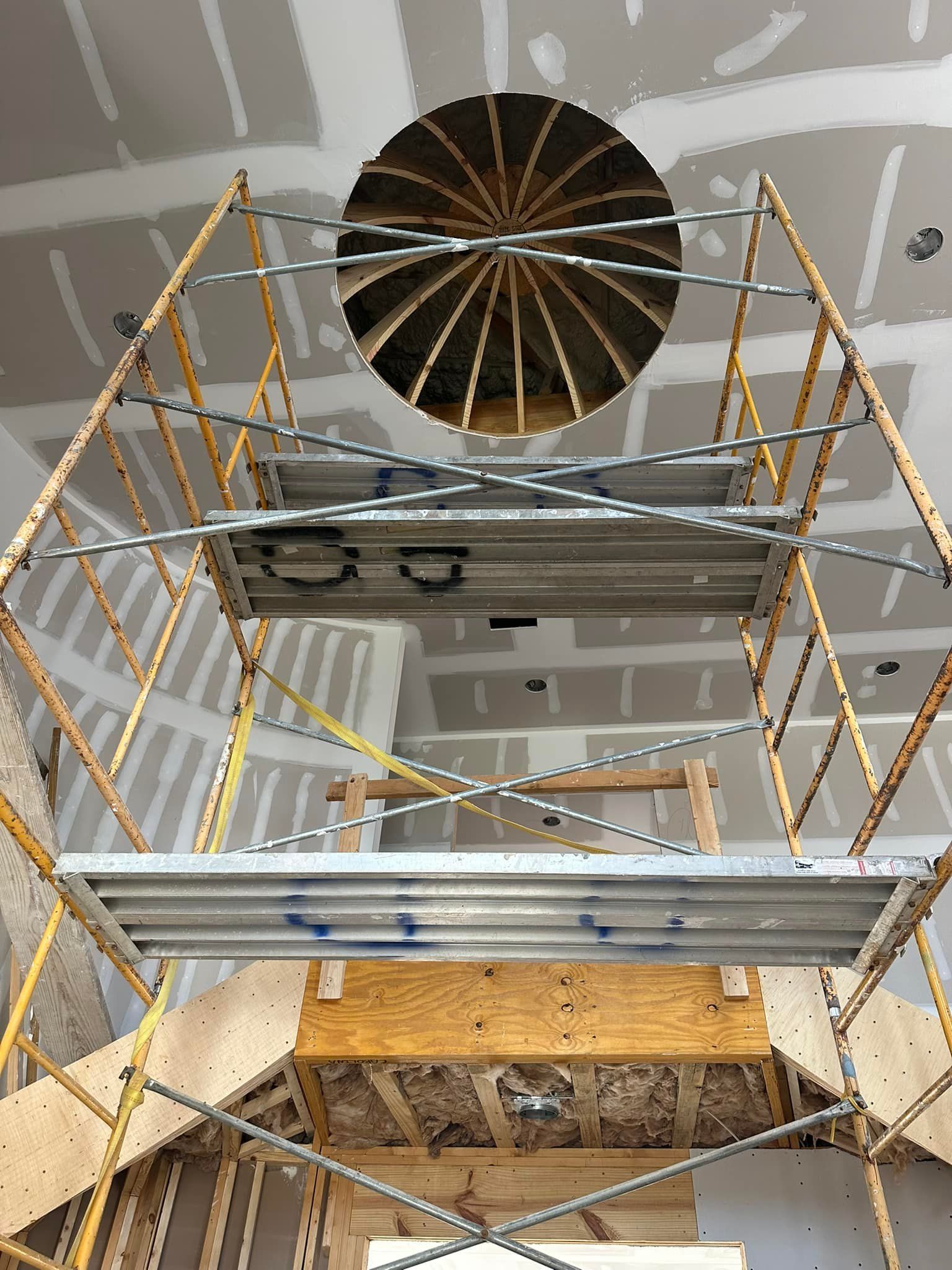 A scaffolding in a room with a round hole in the ceiling.