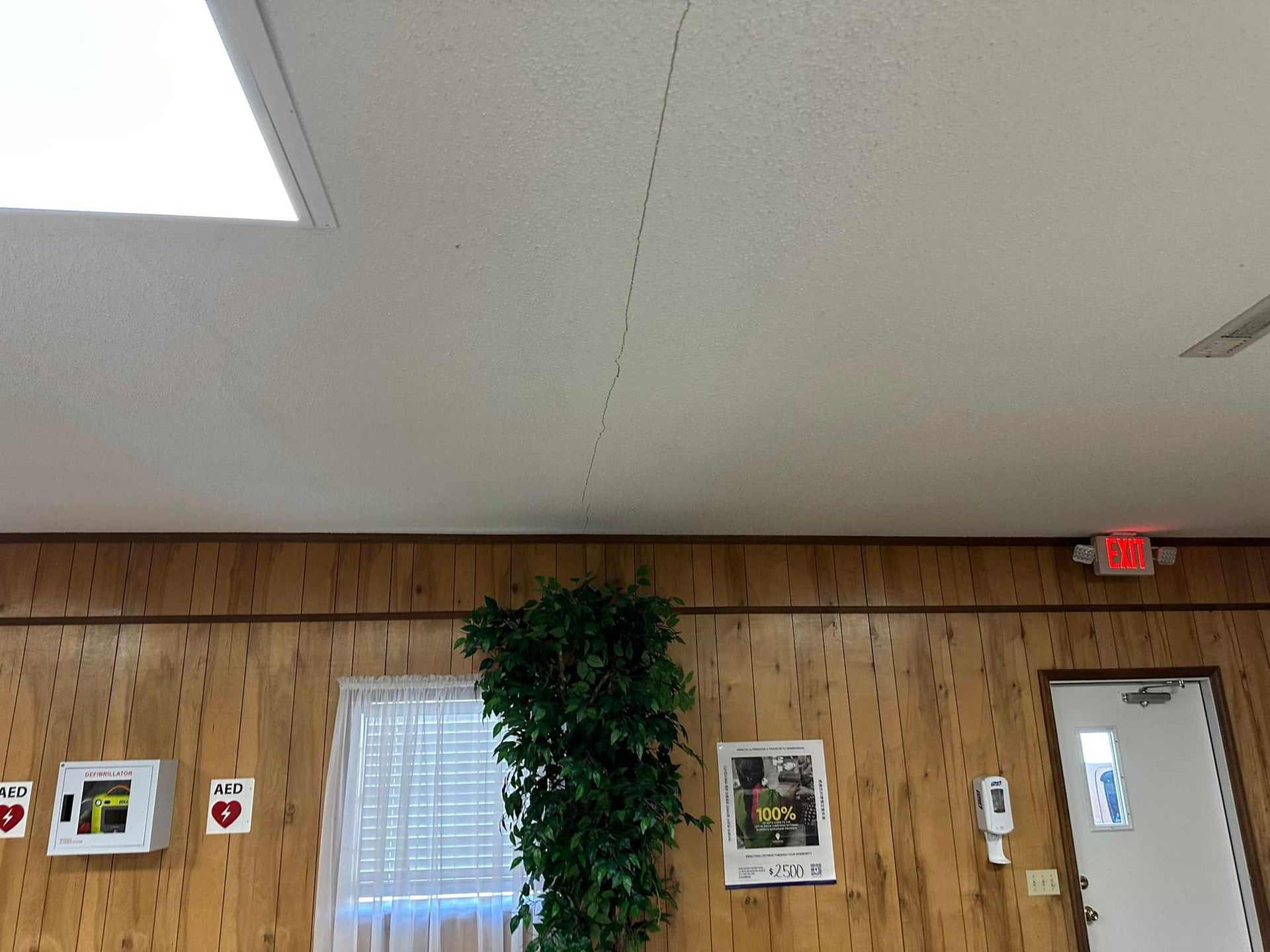 A room with wood paneling and a red exit sign on the ceiling.