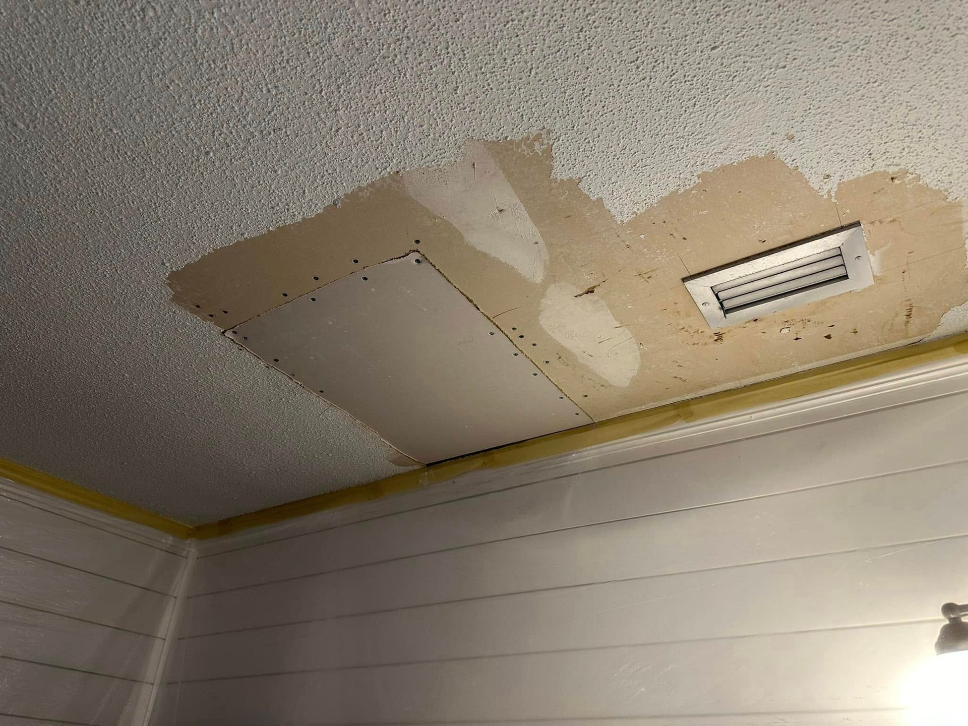 A ceiling with a hole in it and a fan on it.