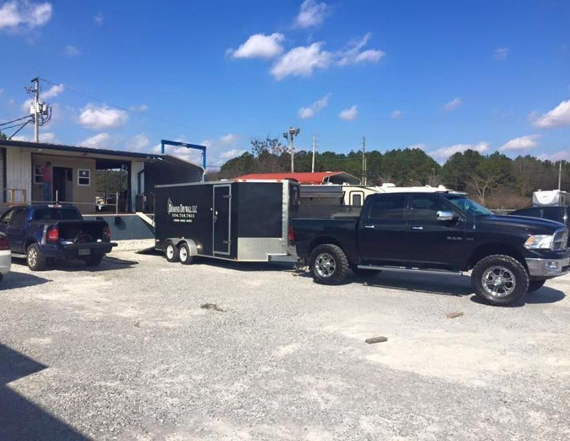 A truck is pulling a trailer in a parking lot.