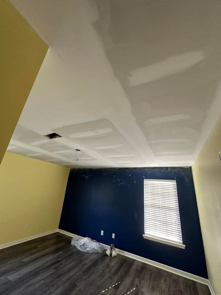 An empty room with a window and a blue wall.