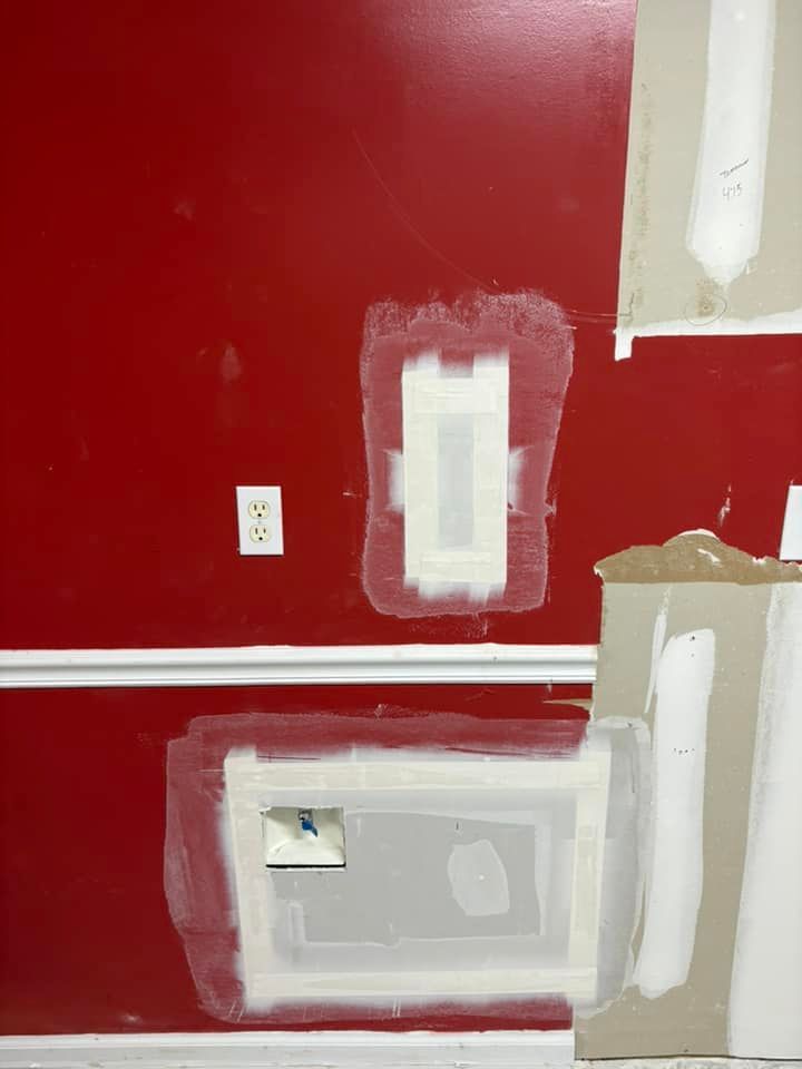 A red wall is being painted with white paint