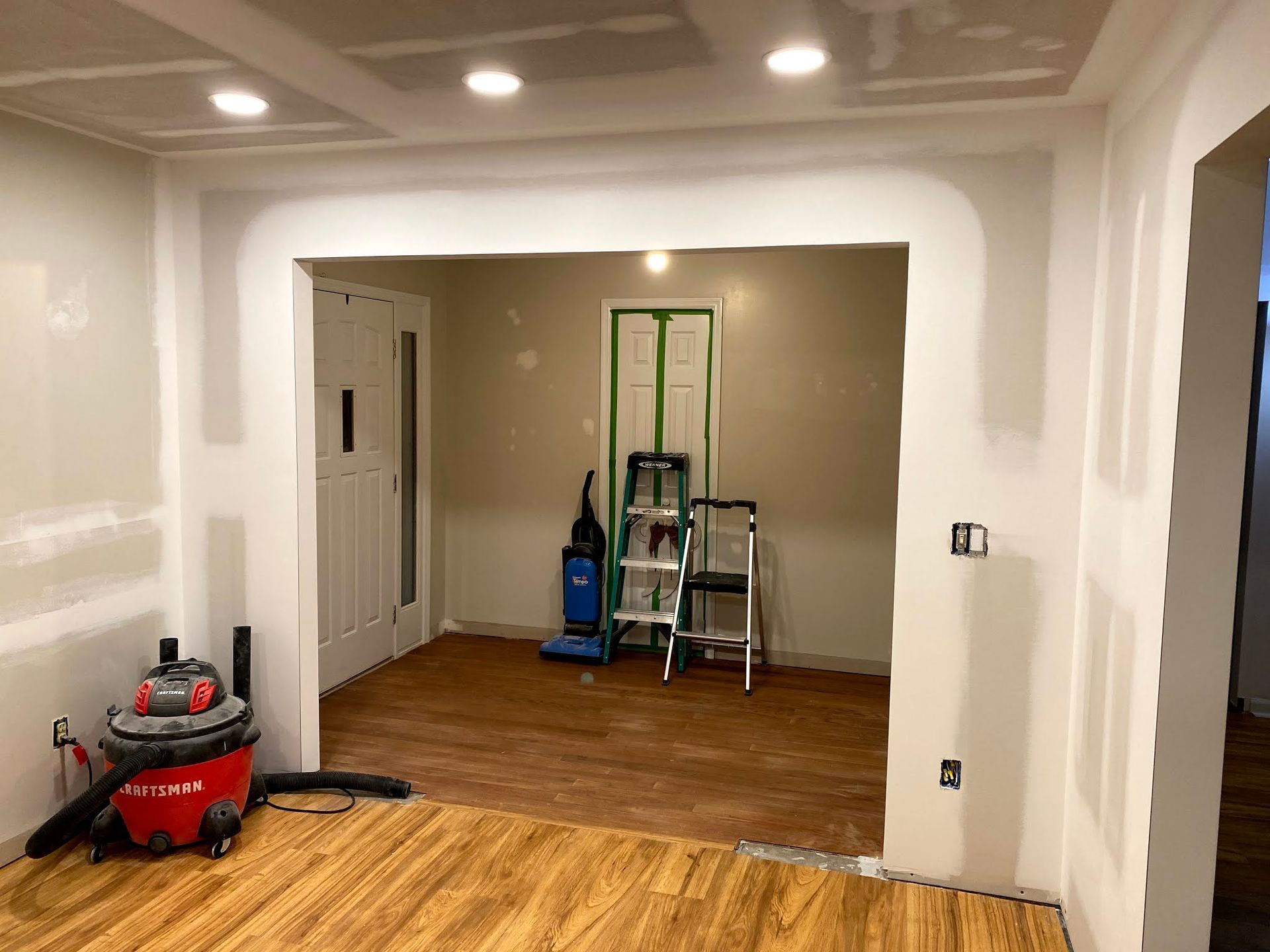 A room with a vacuum cleaner and a ladder in it.