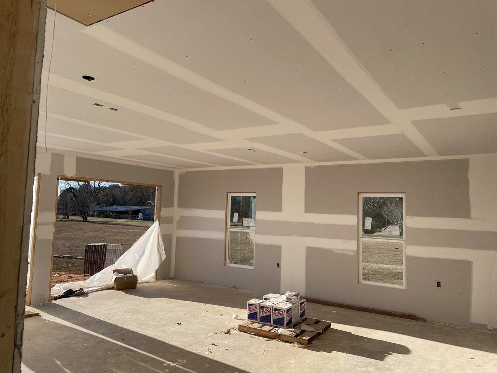 A room in a house under construction with a pallet of paint on the floor.