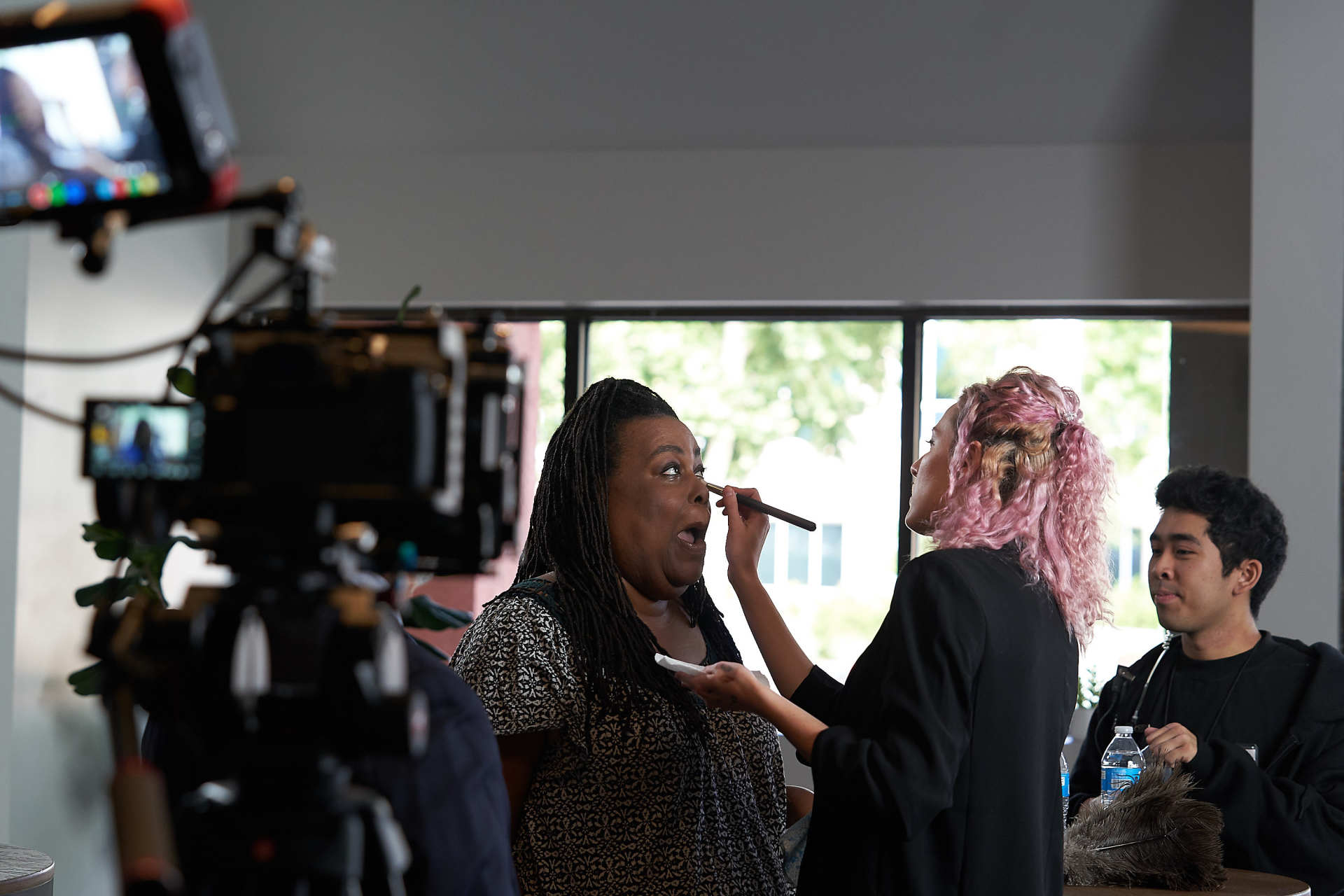 a white woman putting on makeup on a black woman on a film set