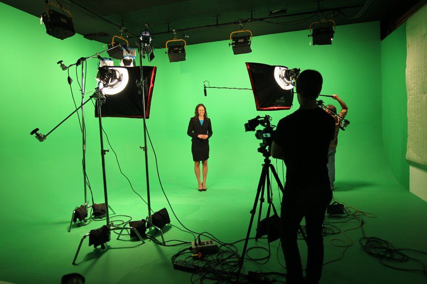 a woman filming a scene in a green screening studio talking to the camera