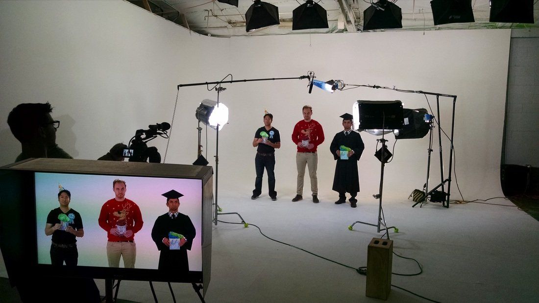 actors filming a scene at a studio with a white backdrop