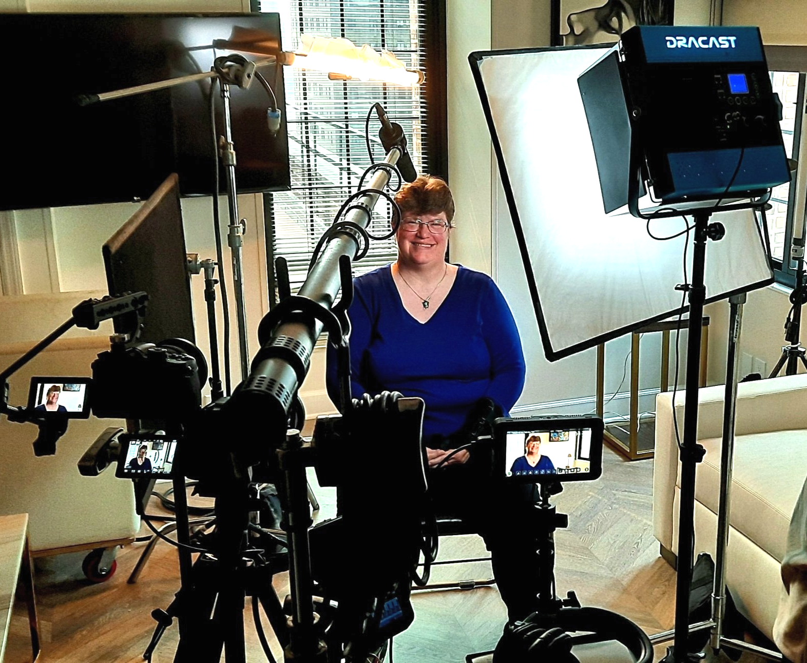 a woman sitting with camera equipment around her for an interview