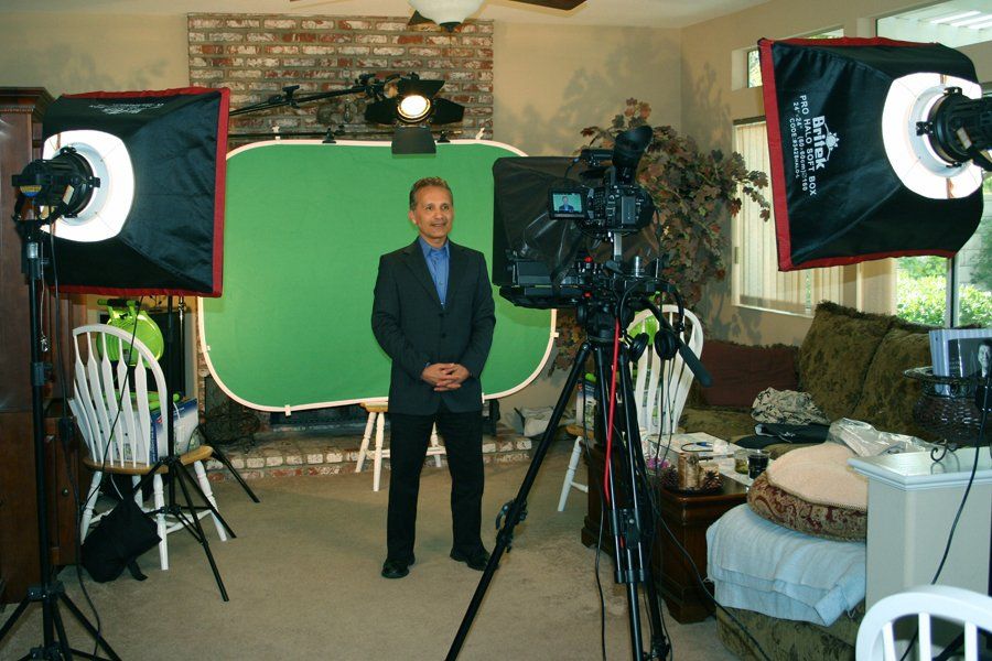 a man standing in front of a portable green screen studio filming a scene