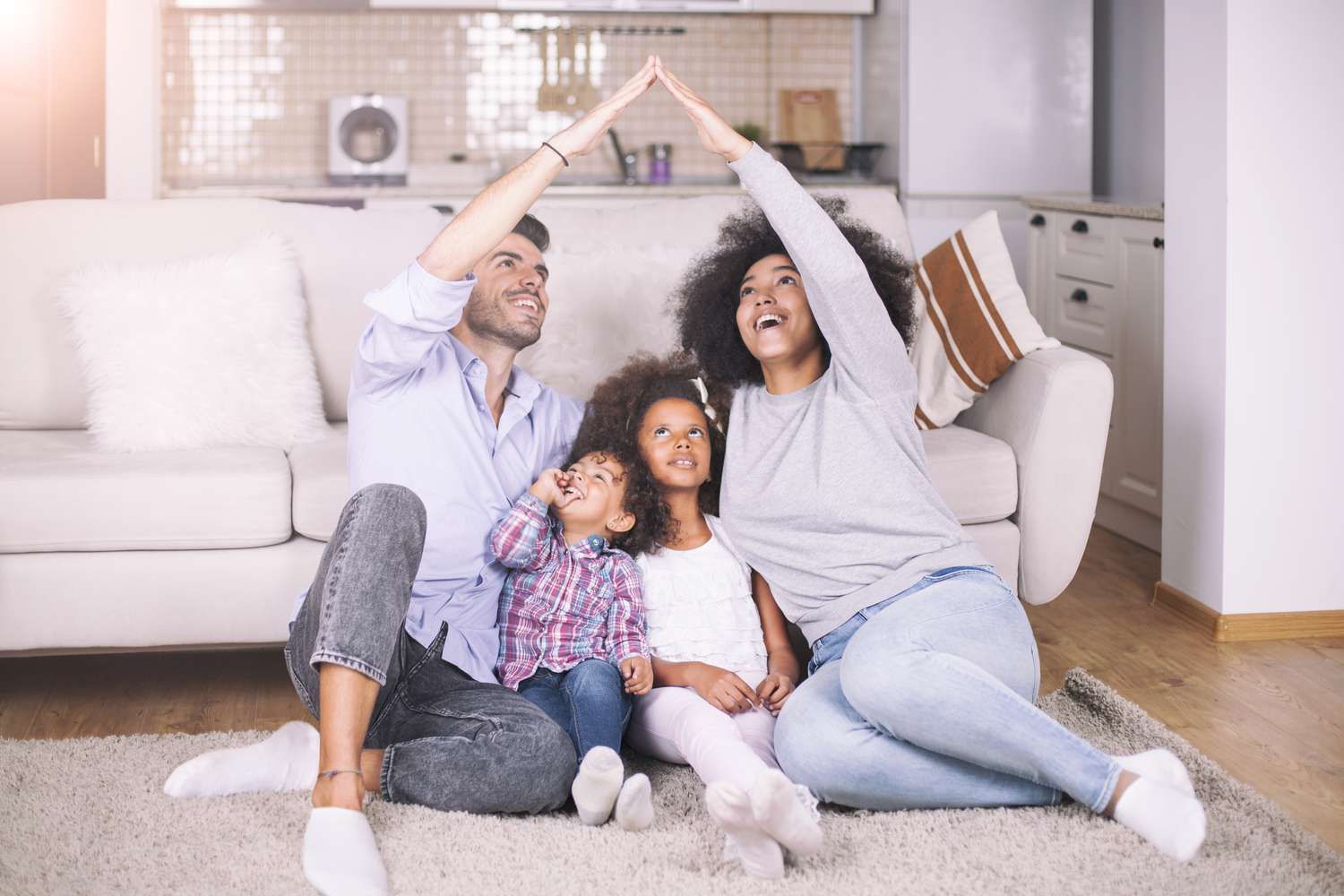 A family is sitting on the floor in a living room giving each other a high five.