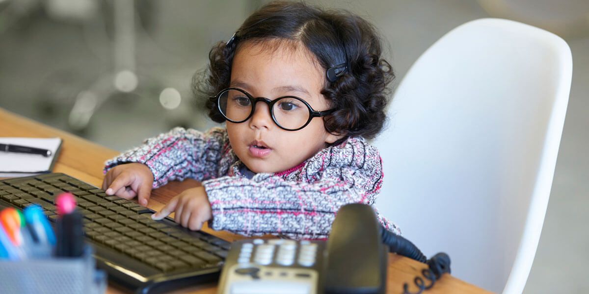 Little child with glasses typing on a keyboard