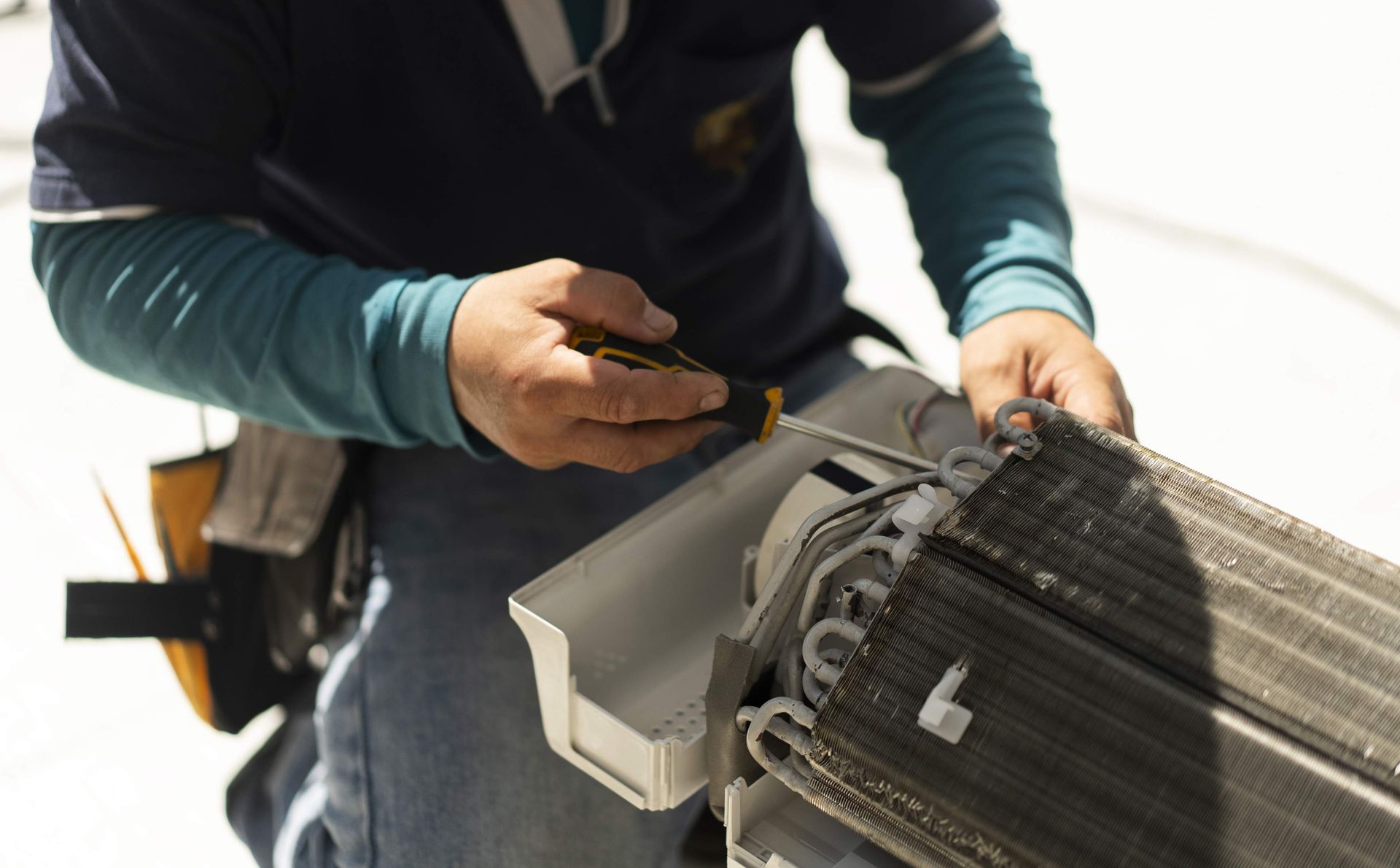 The hands of a mechanic man removing the system and part of an air conditioner