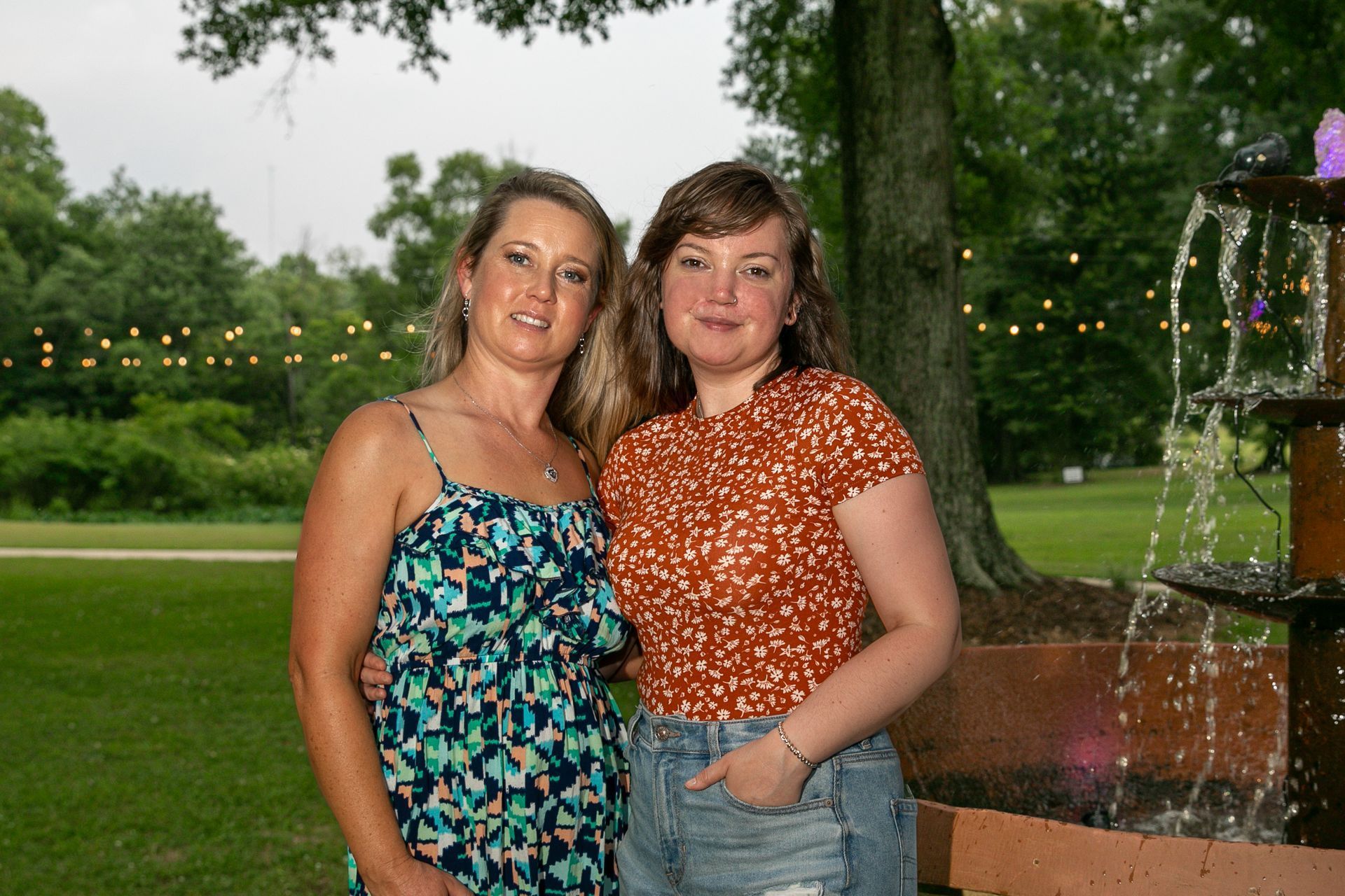 Two women standing next to each other in front of a fountain