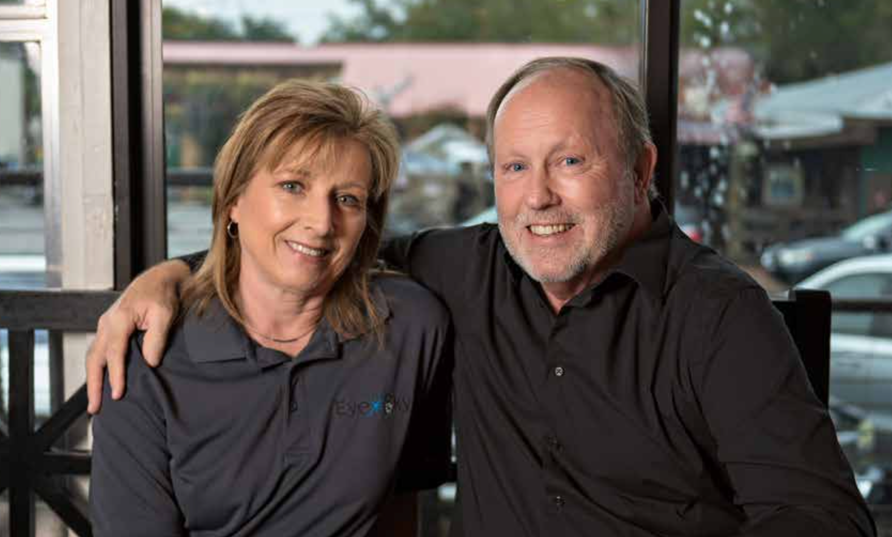 A man and a woman are posing for a picture in front of a window
