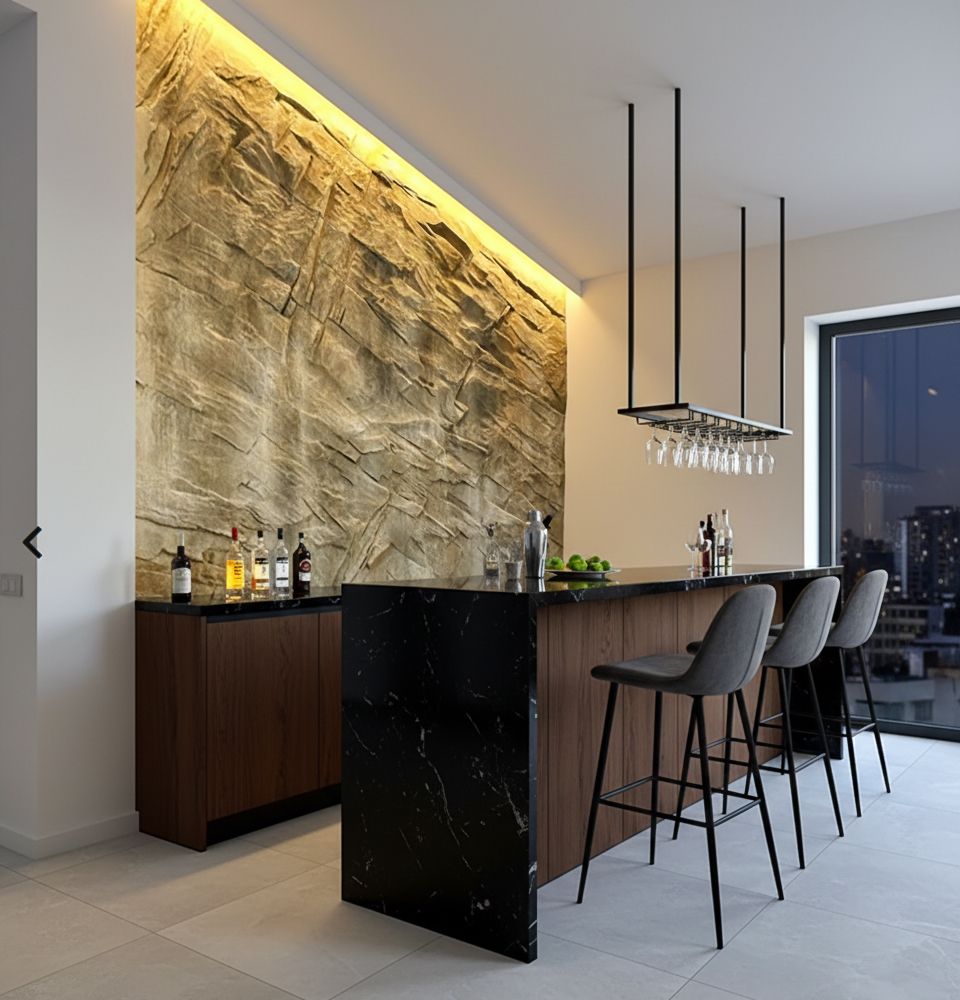 Bar con fondo de pared de piedra, iluminado con luz cenital. Cuenta con botellas, taburetes y copas colgantes.