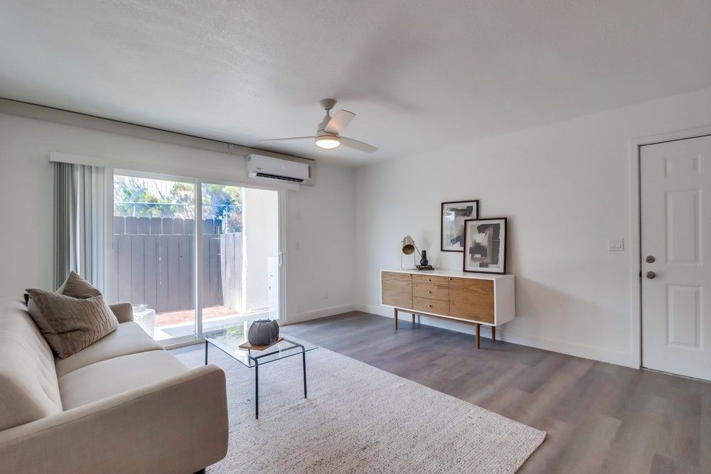 Photo showing a living room with a sliding glass door leading to a patio
