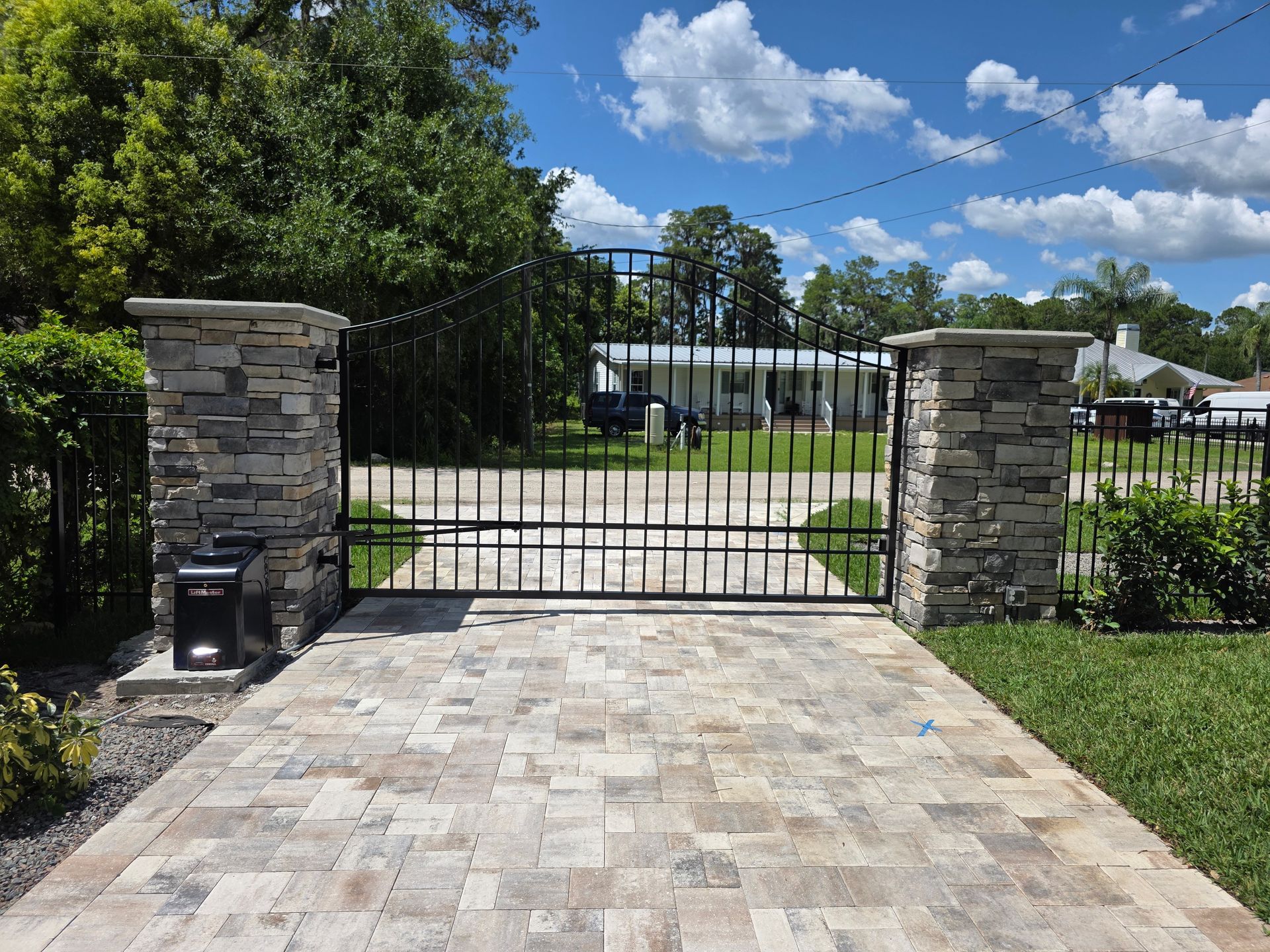 Stone pillars with black metal gate and driveway entrance.