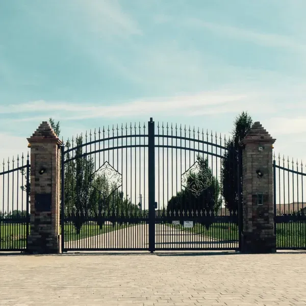 A wrought iron gate with a stone pillar in front of it