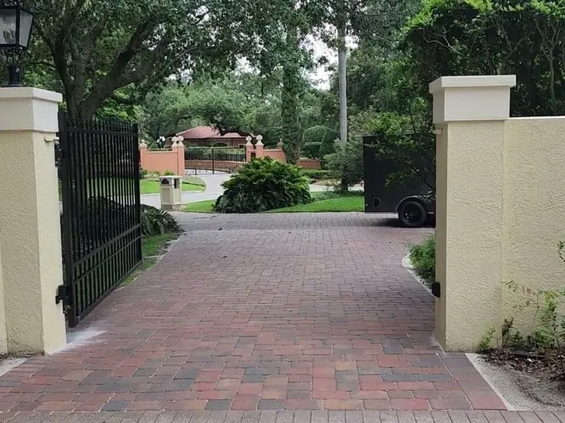 A brick driveway leading to a gated entrance
