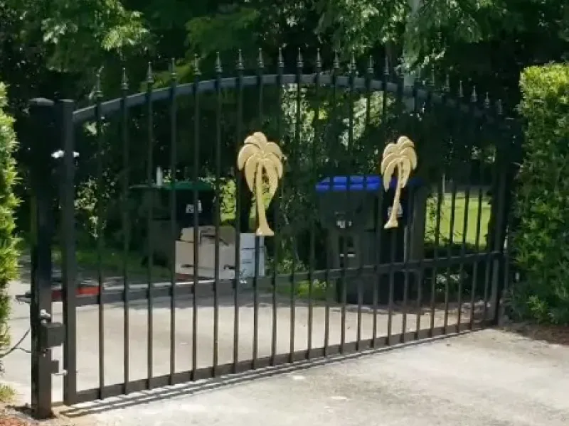 A black gate with palm trees painted on it